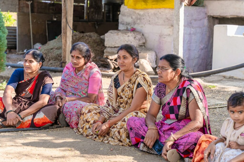 बिहार और ग्रामीण भारत की महिला मतदाता समुदाय में बैठी हुईं, जो राजनीतिक प्रक्रिया में सक्रिय भागीदारी का प्रतीक हैं